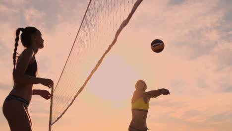 Beachvolleyball-Match-Mädchen-Schlagen-Den-Ball-In-Zeitlupe-Bei-Sonnenuntergang-Auf-Dem-Sand